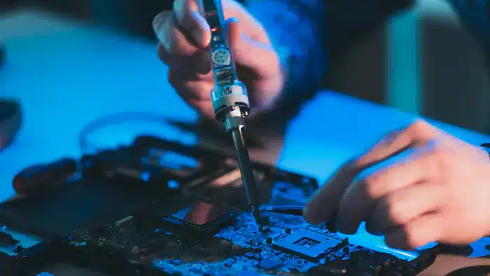 Technician performing soldering repair on a gaming gadget.